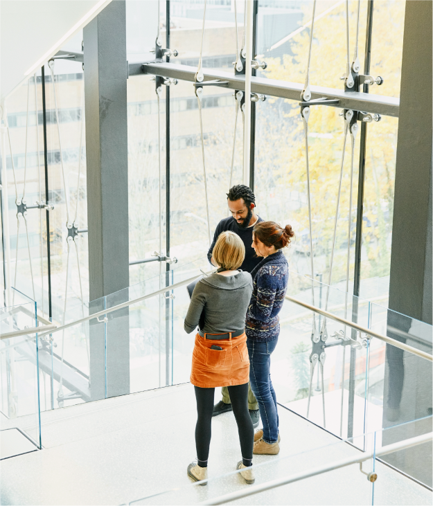 Group of three coworkers having conversation in a stairwell of office building